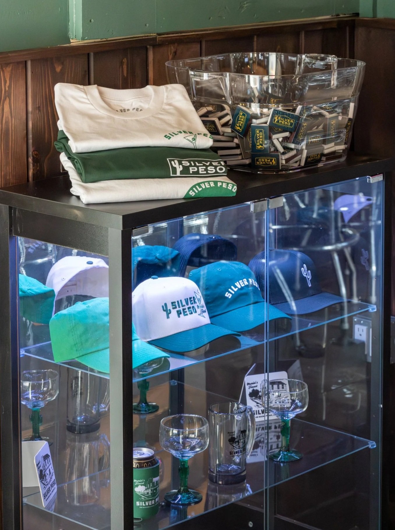 merchandise, glassware, souvenirs, hats, and t-shirts branded with Silver Peso logo