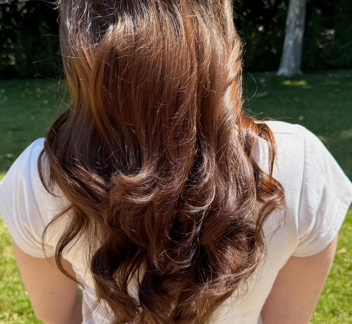 Elegant special occasion updo by Marin hairstylist Meg Sweeney, featuring a smooth low bun with floral accents for weddings and formal events in Mill Valley, California.
