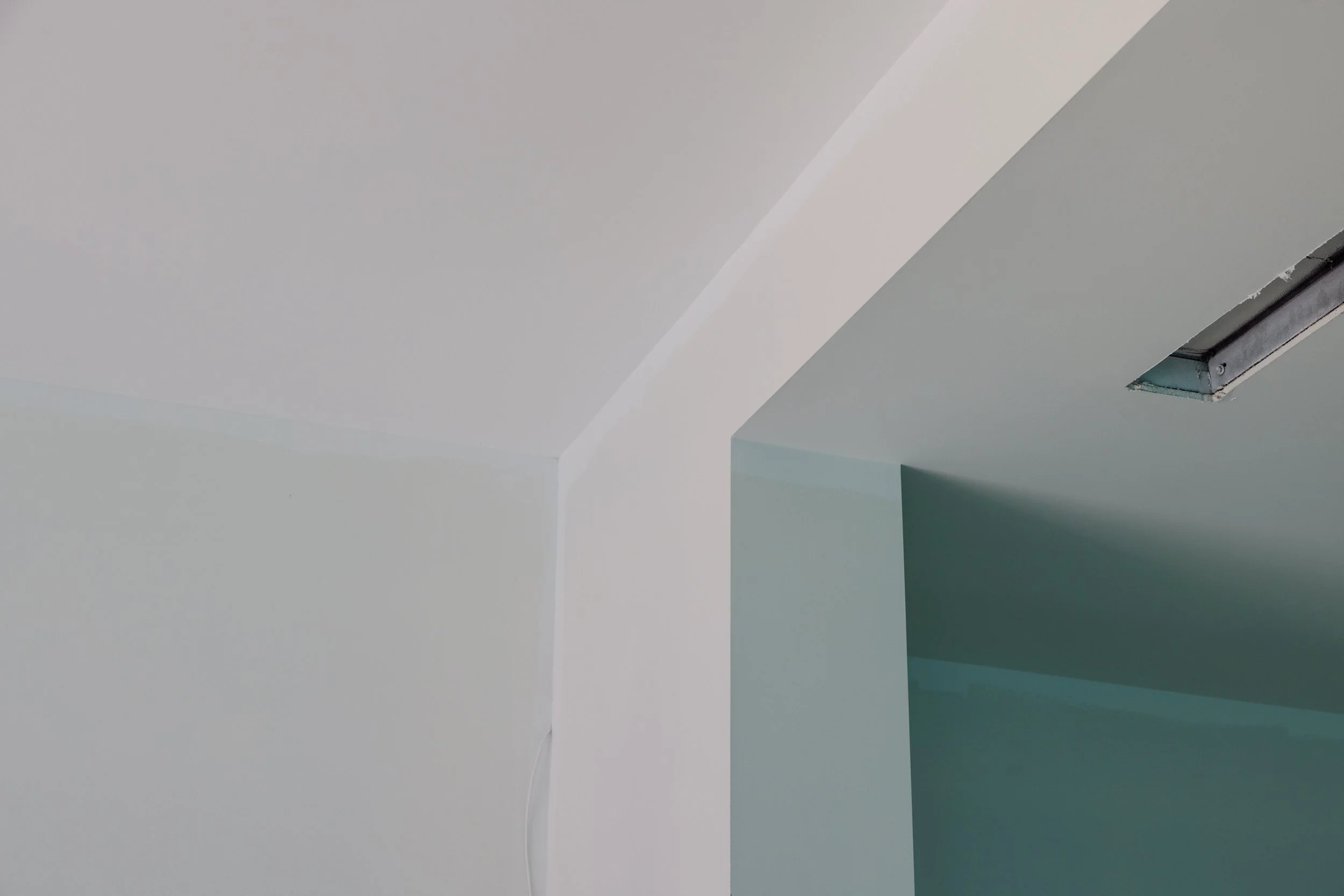 Ceiling with white paint, smooth curves, and a rectangular opening with visible hardware.
