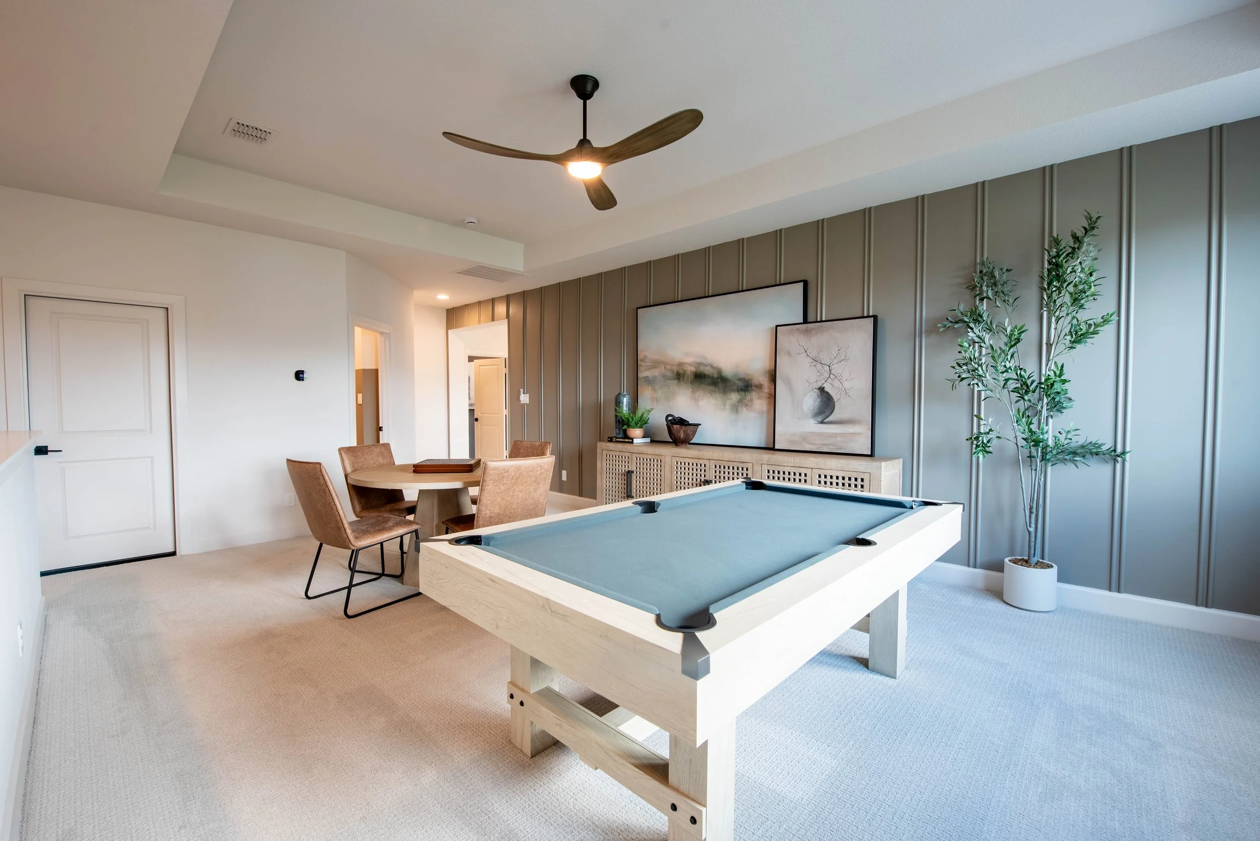 Living room with a ceiling fan, wall art, plants, a round dining table with four chairs, and an air hockey table.