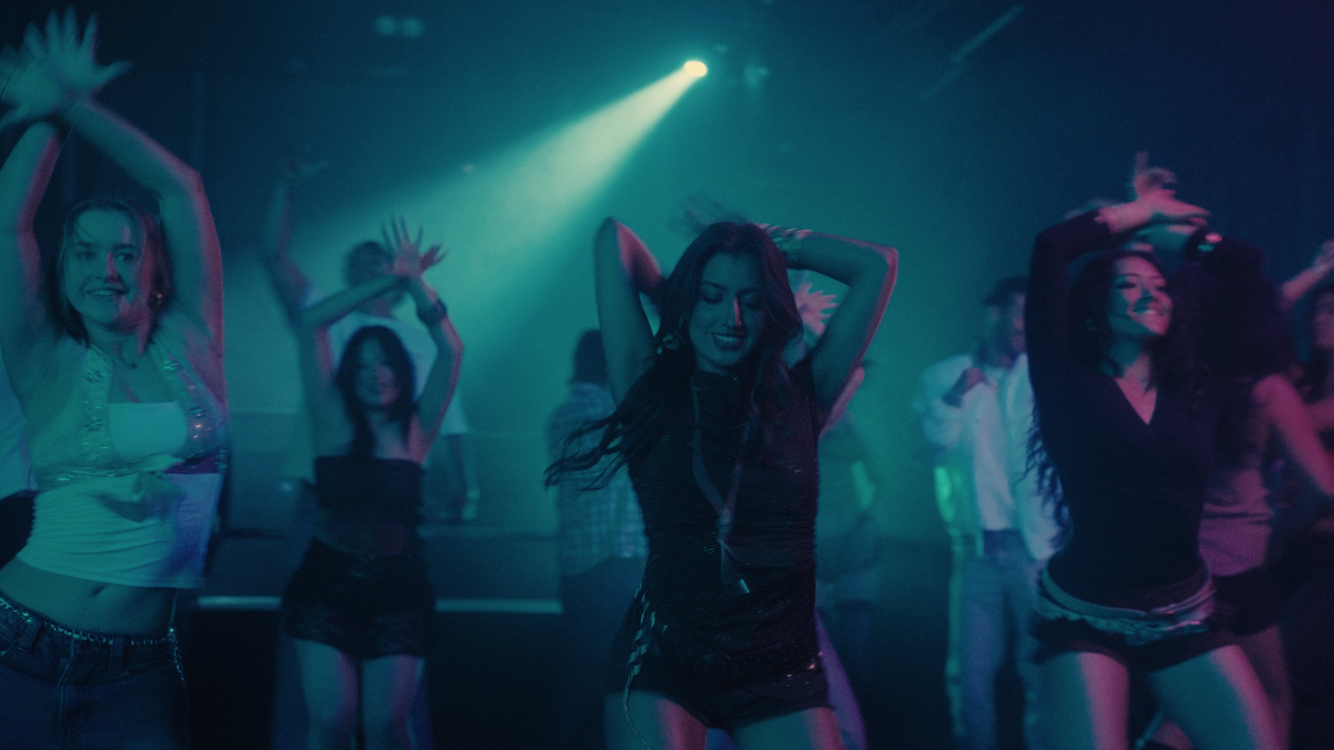 Group of young people dancing at a nightclub with colorful blue and green lighting. Take Me Away music video Aanya Melbourne Music Video.