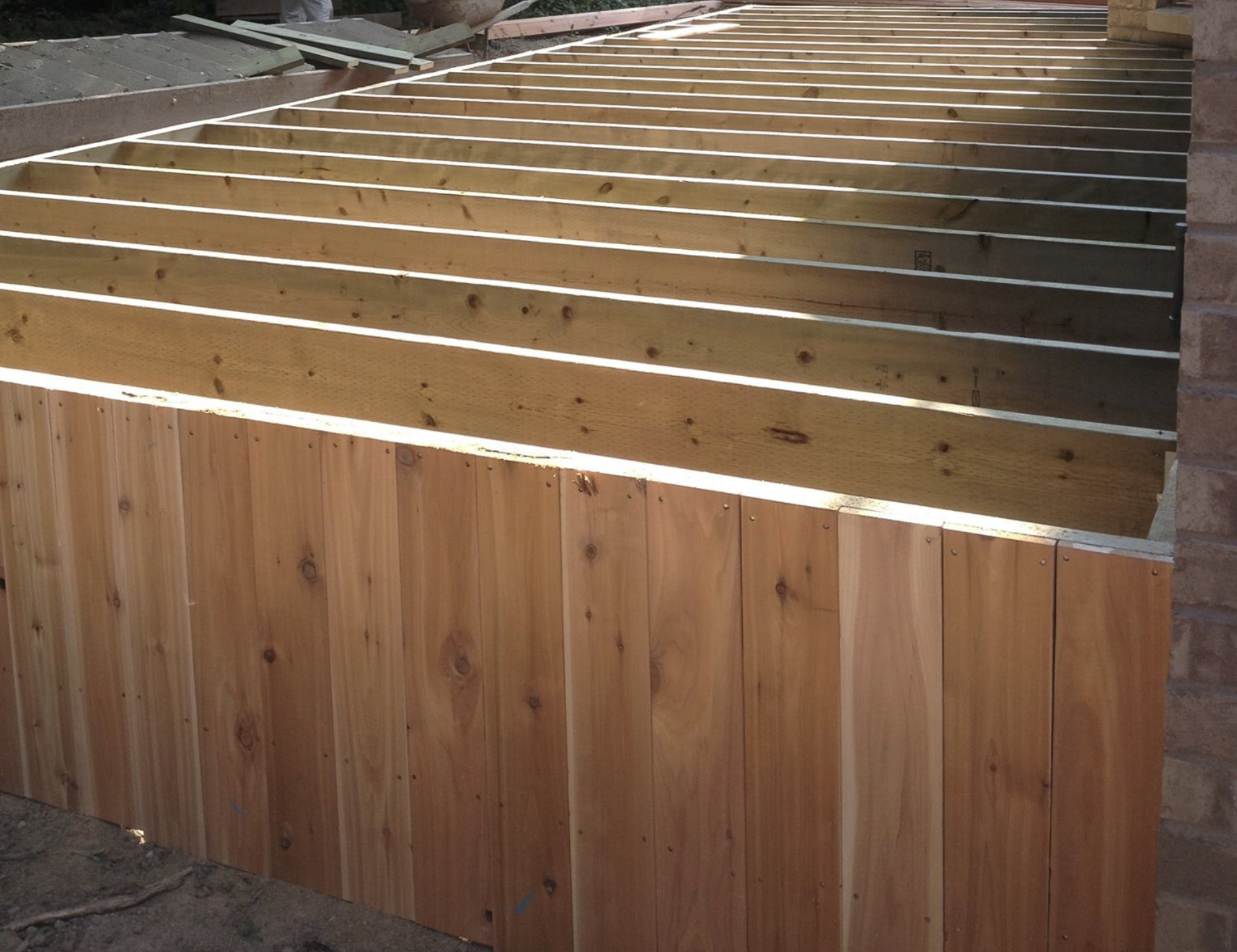 Wooden fence panels under construction with horizontal slats and partially installed vertical supports.