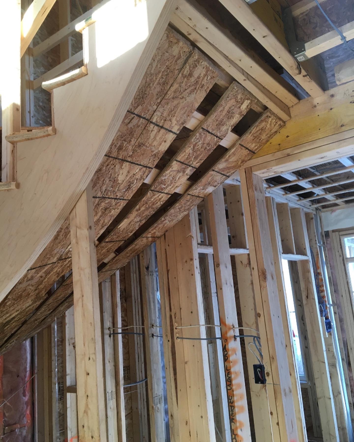 The interior of a building under construction showing wooden framing, electrical wiring, and insulation.