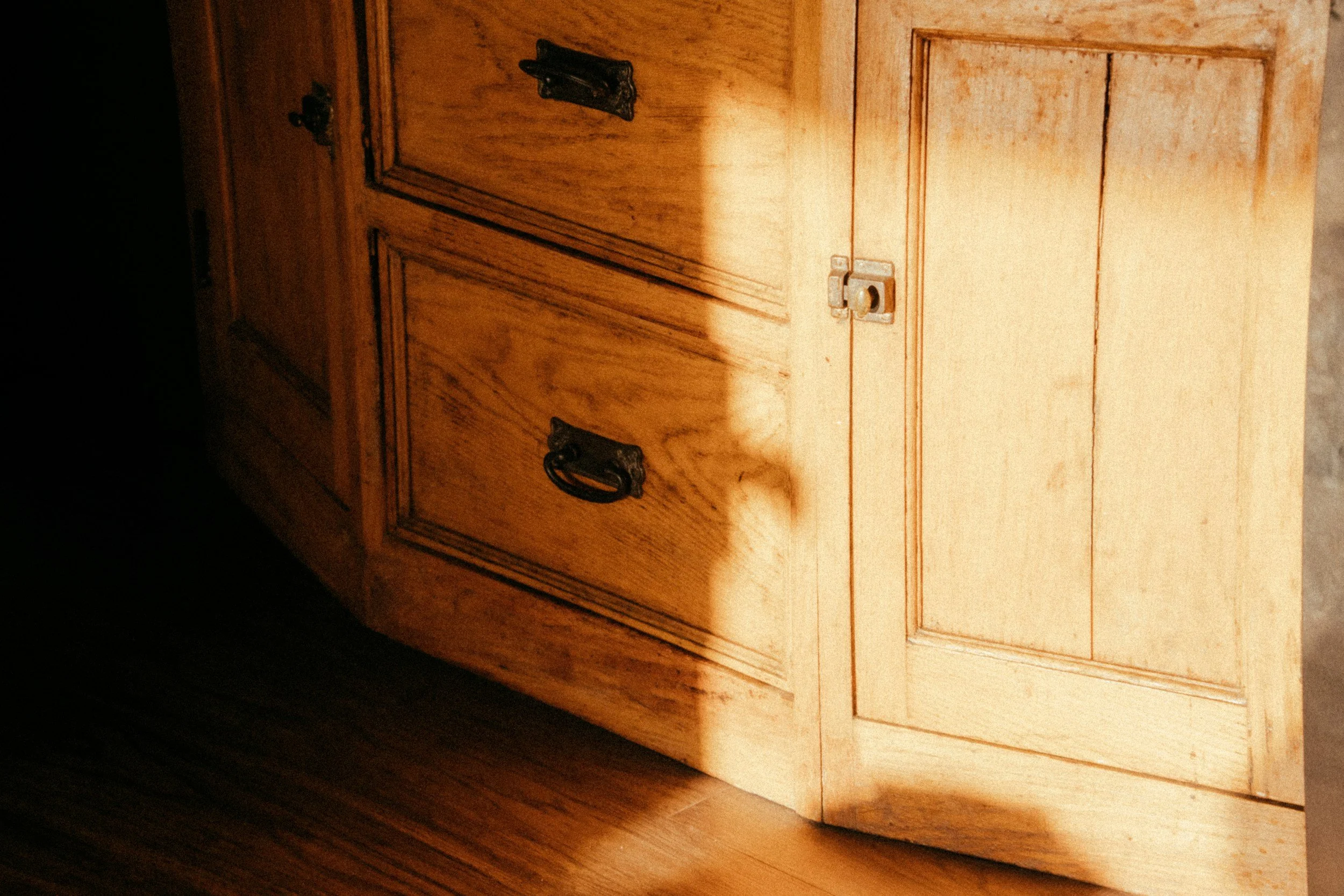 Close-up of a wooden cabinet with metal handles and a lock.
