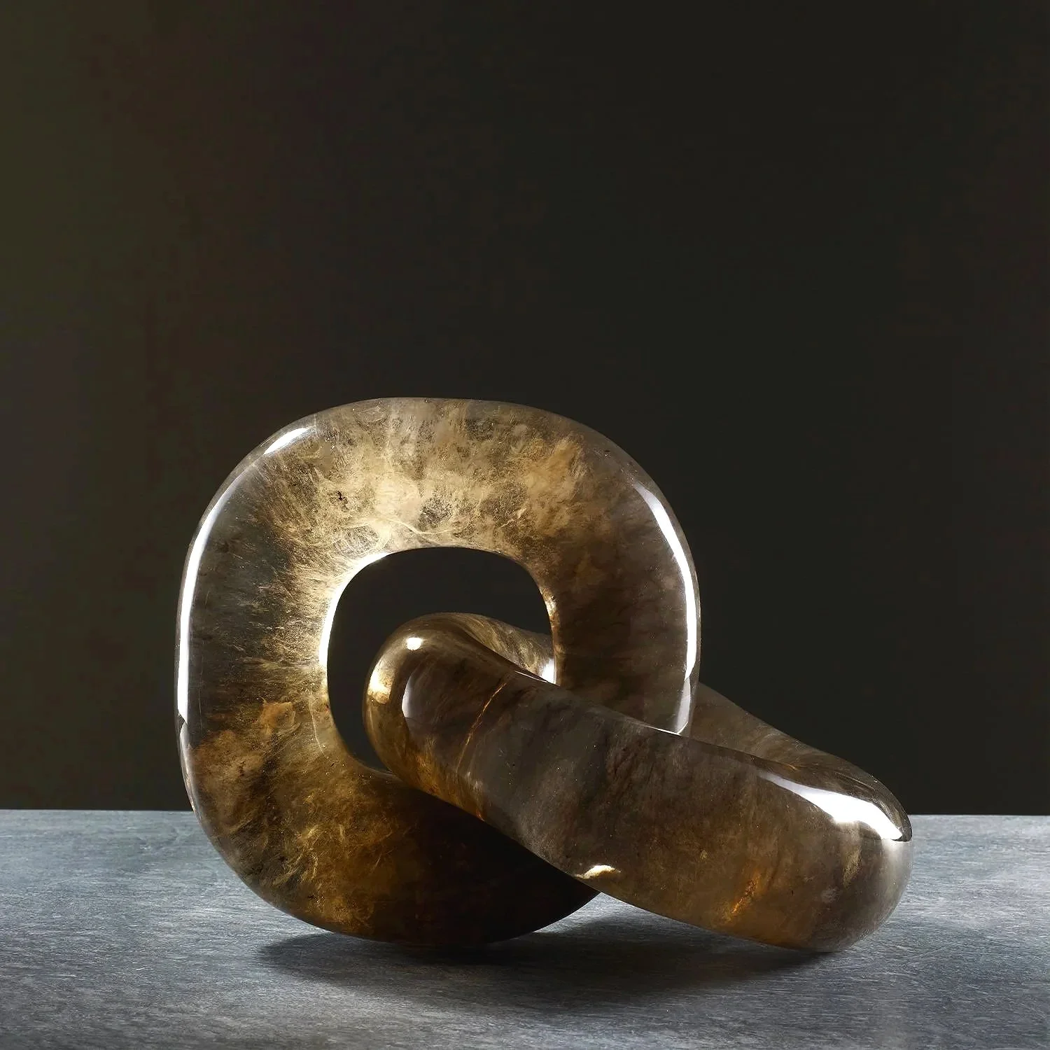 Close-up of a brass spiral sculpture on a dark surface with a dark background.