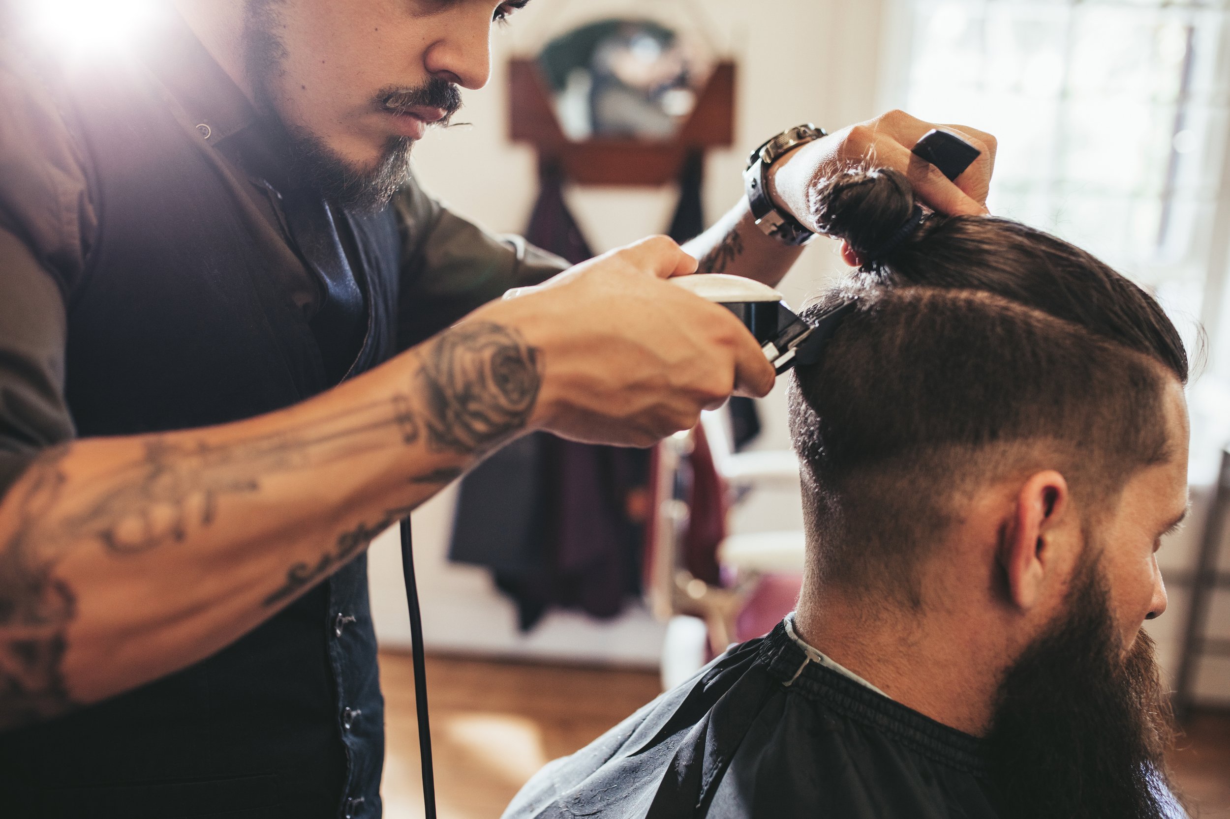 Barber giving a haircut to a male customer inside a barbershop.