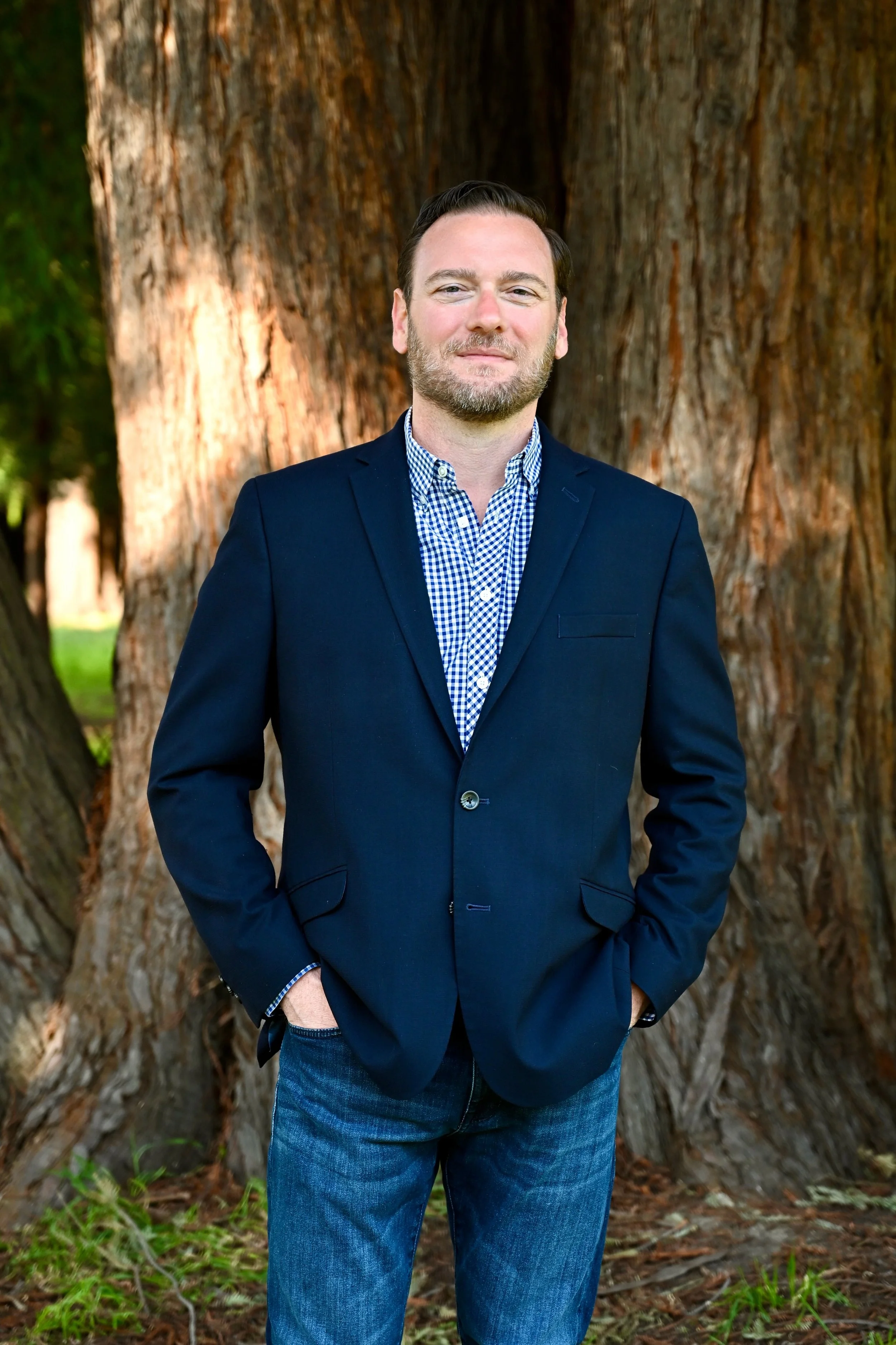 Michael DeSimone in a blue blazer and jeans standing in front of a tree