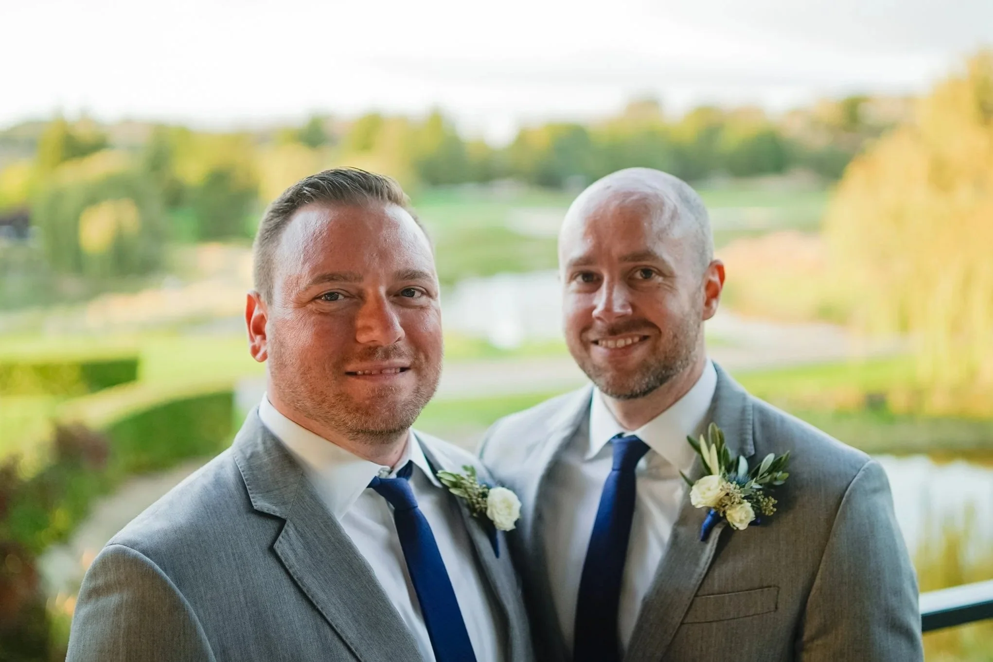 Michael and his husband Daniel on their wedding day wearing matching gray suits and blue ties