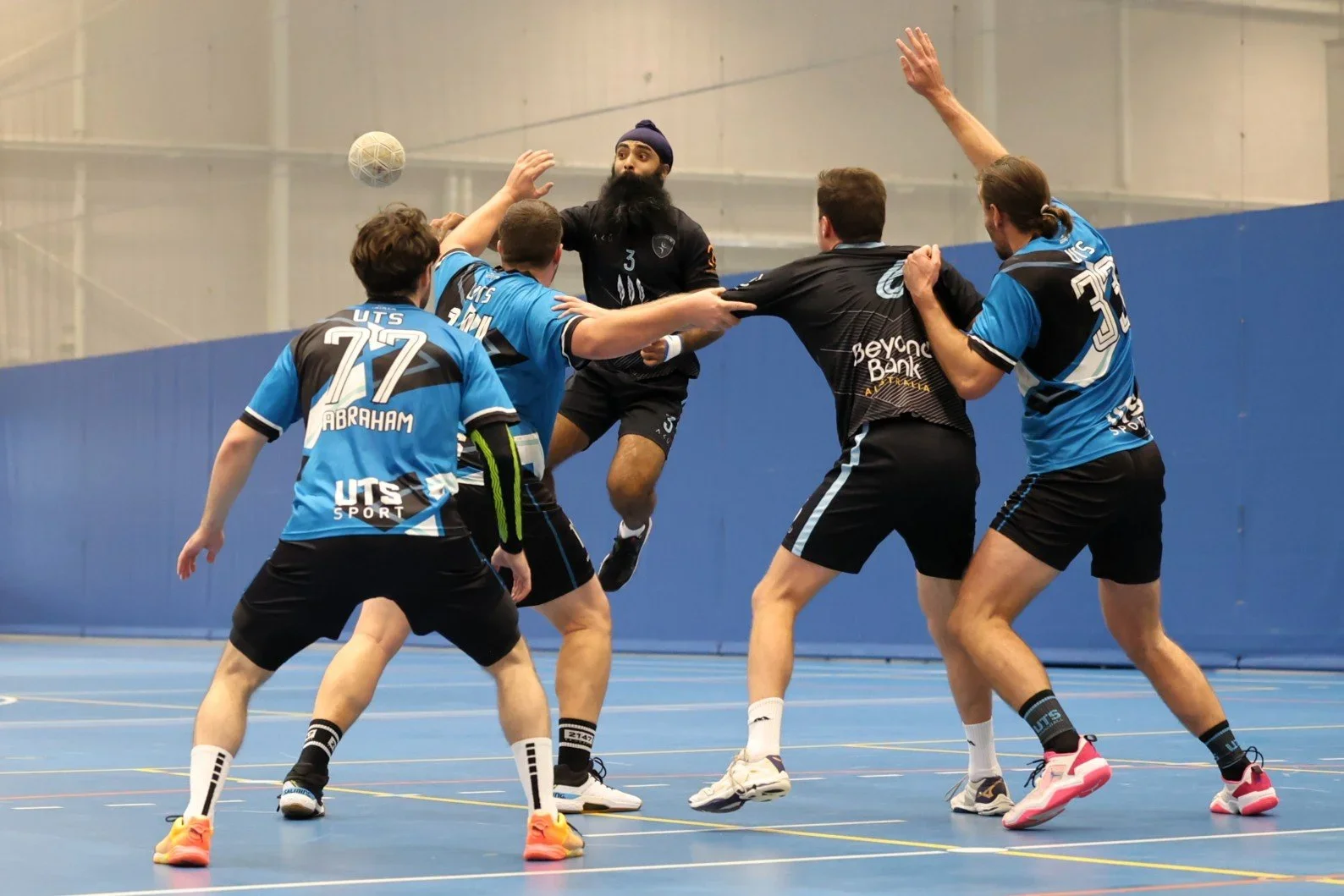 Action Shot of a player passing the ball whilst in mid-air around a tight defence.