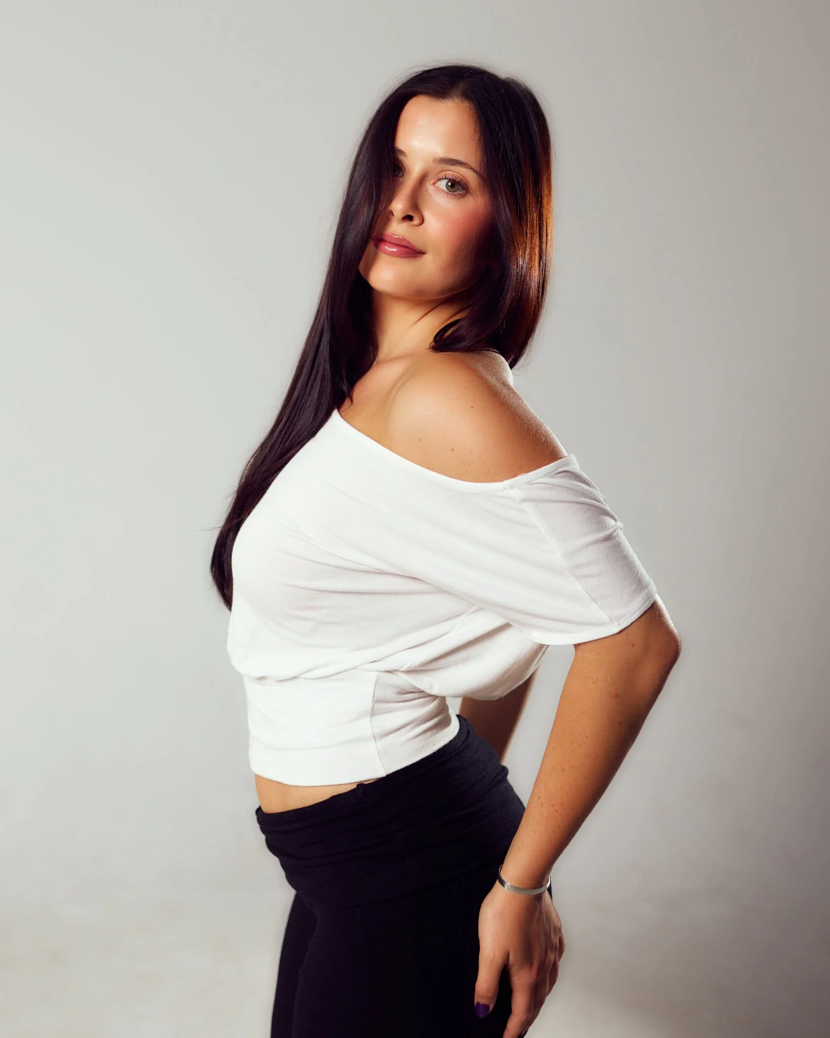 Denver model portfolio photograph of female model posing in a white off-shoulder top against a neutral backdrop.