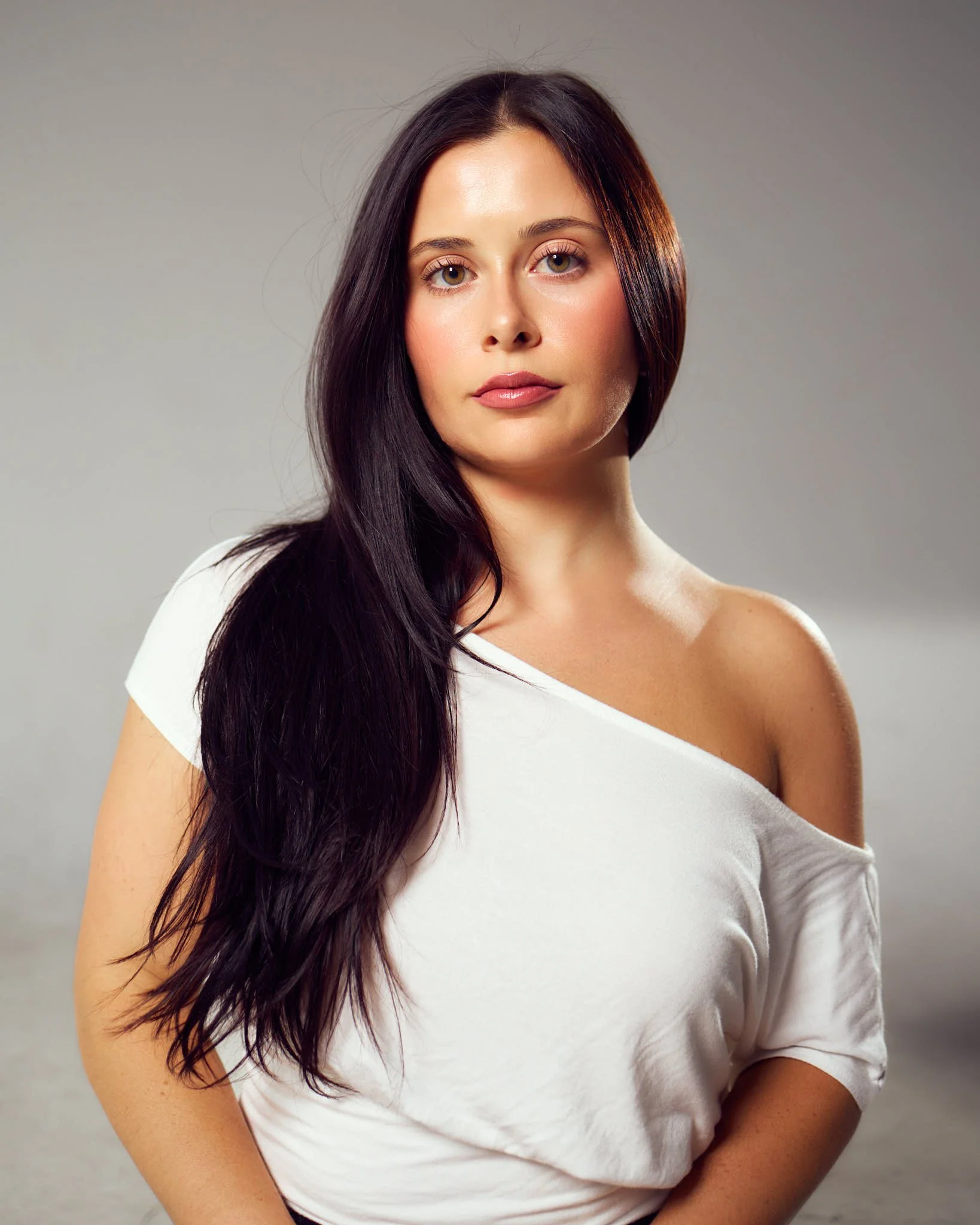Studio model portfolio portrait featuring female model with long dark hair and white off-shoulder top.