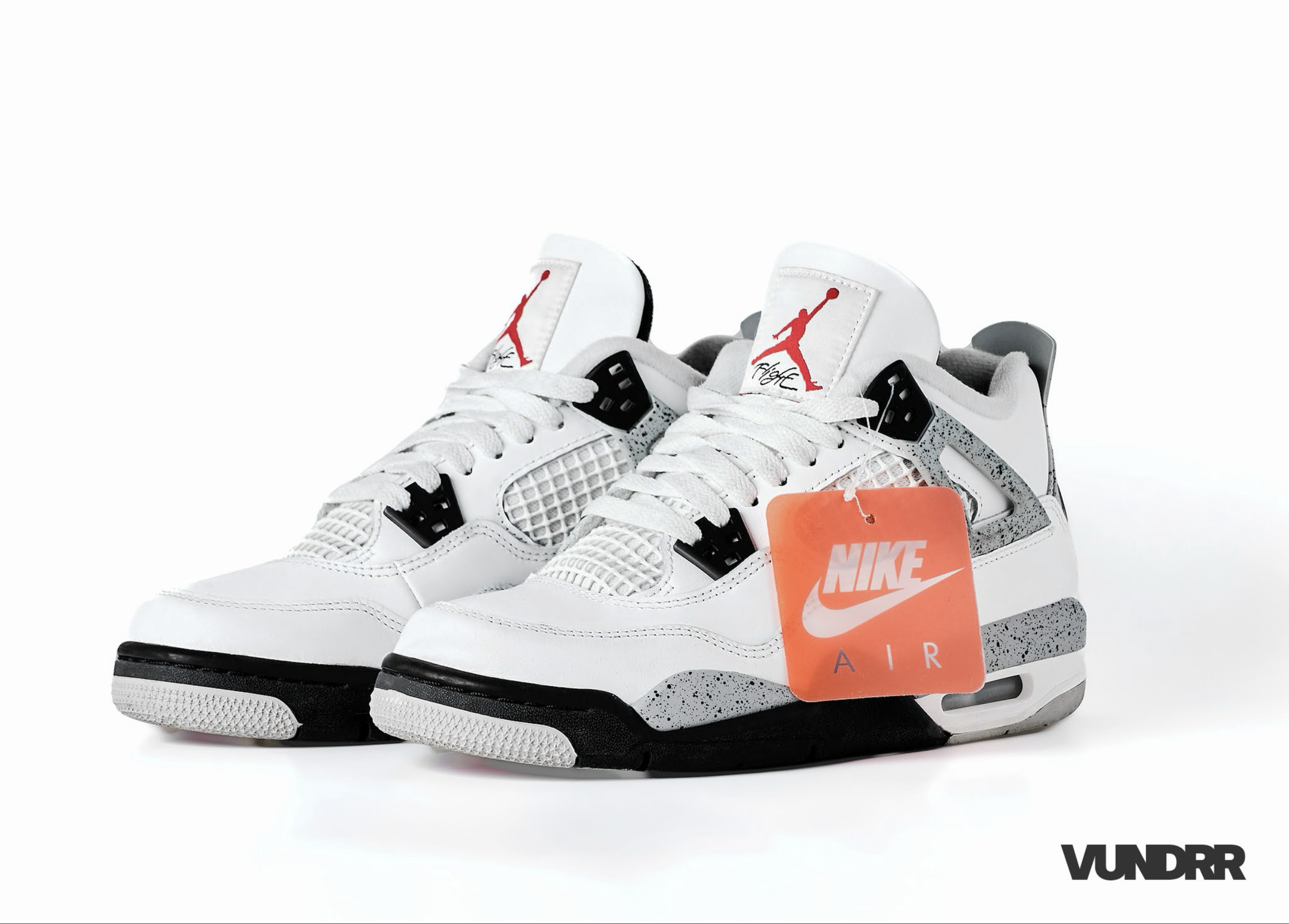 Close-up of a pair of white Nike Air sneakers with black accents and red Jumpman logos on the tongues, against a white background.