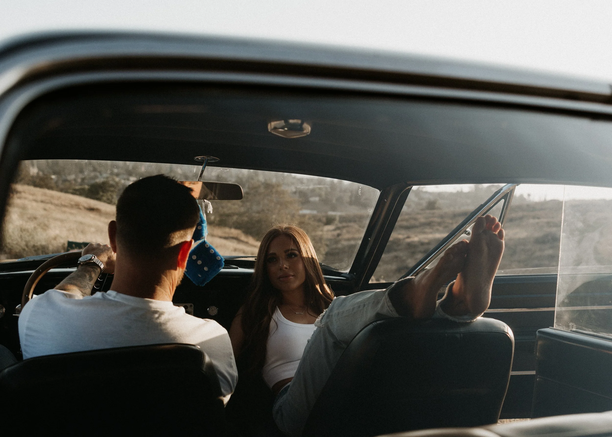 Couple sitting inside a vintage car with warm light coming through the windows.