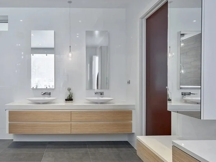Modern bathroom with double vanity and two vessel sinks, large mirror, wooden drawer cabinet, gray tiled floor, and minimal decor.