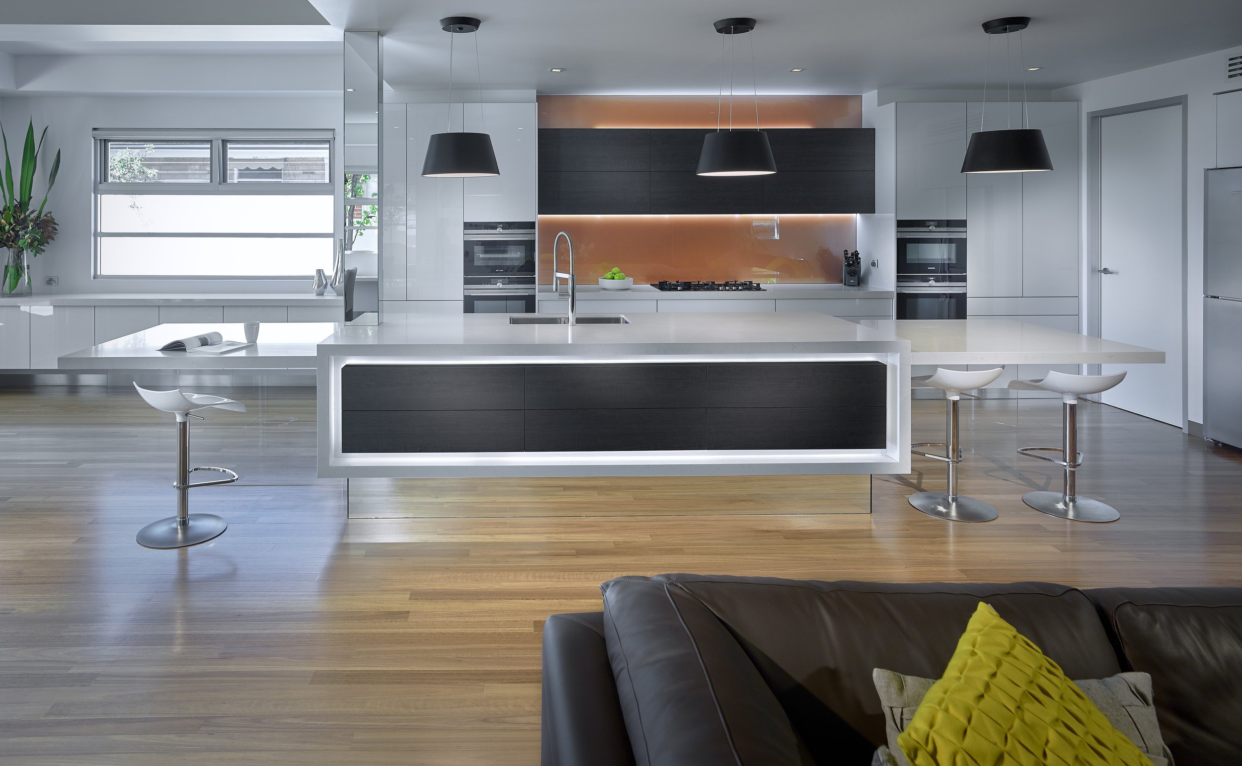 Award winning kitchen with seating at each end supported on toughened vertical glass panels