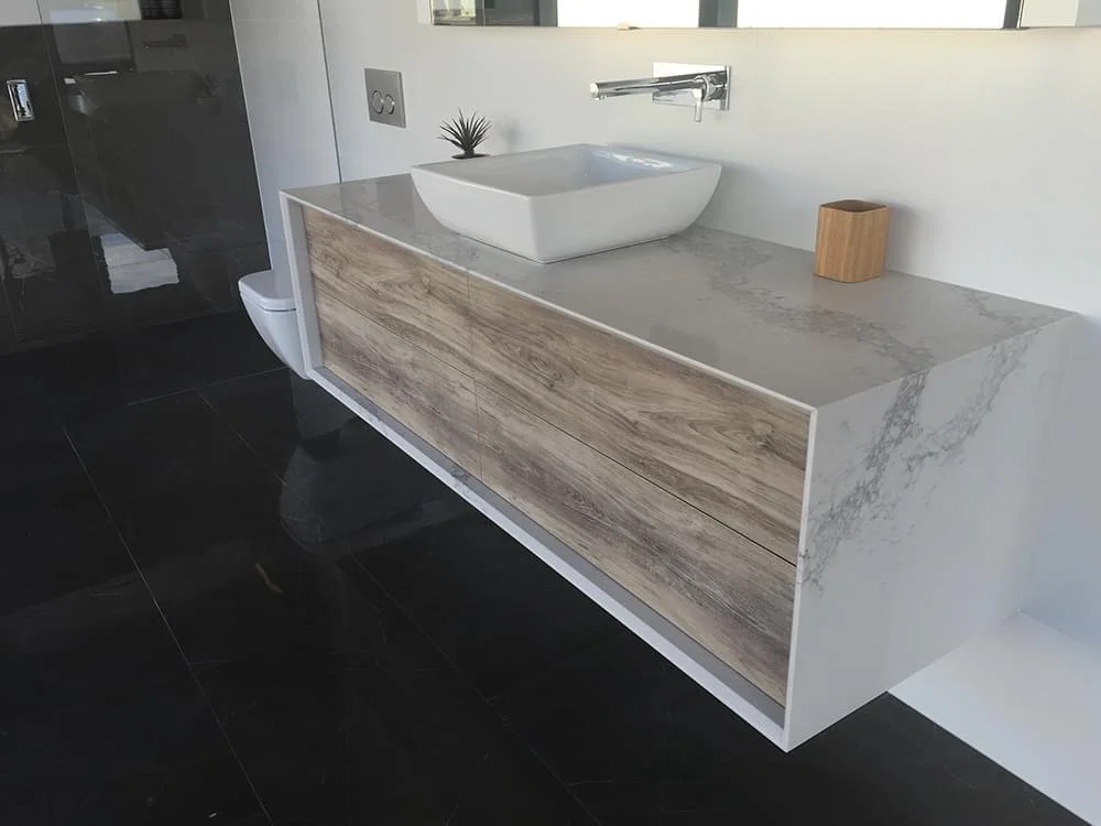 Sleek custom-made bathroom vanity wrapped in marble with new age veneer drawer fronts and Blum soft -close drawers