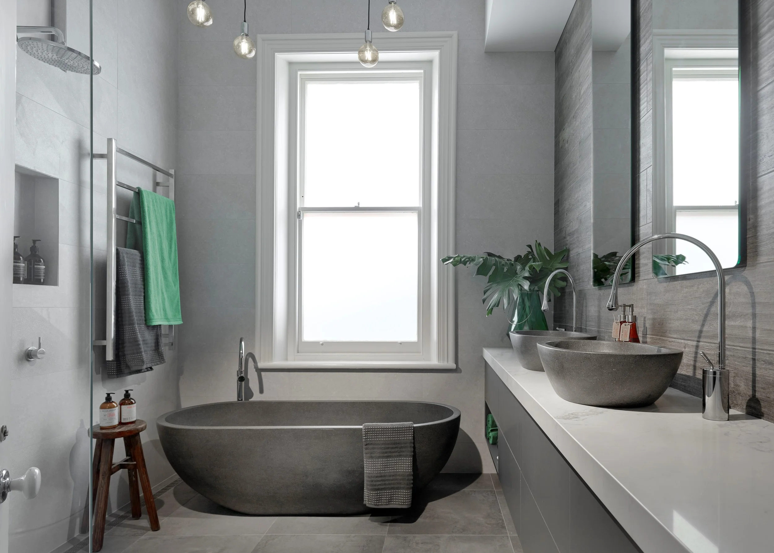 Stone bath and basins, custom vanity cabinetry, feature over bath lighting, industrial and edgy look and style.