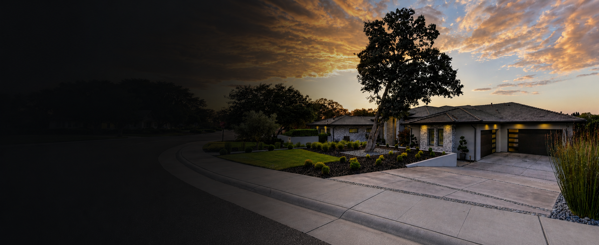 Modern house with landscaped front yard, trees, and driveway during sunset, with the sky partly cloudy.