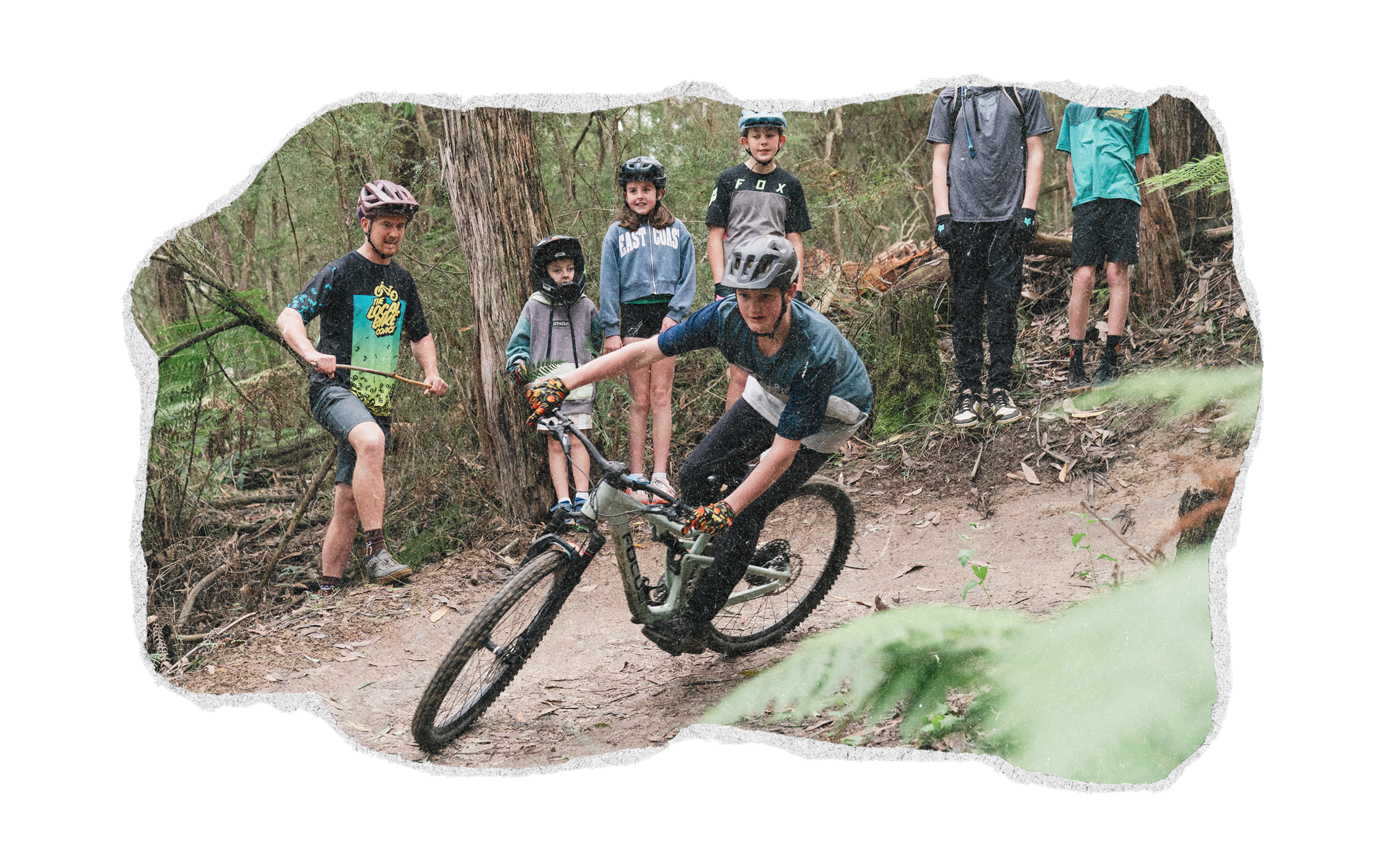 Group of children wearing helmets and riding mountain bikes on a forest trail.