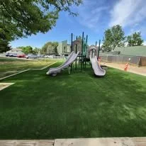 Playground slide with two slides and a climbing structure in a park.
