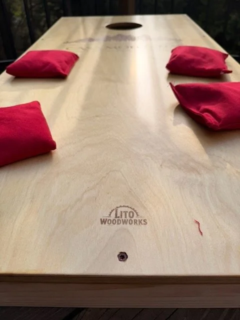 Close-up of the playing surface showing the Lito WoodWorks brand mark and red bean bags, photographed at the Casa Montaña property in Placerville, California.