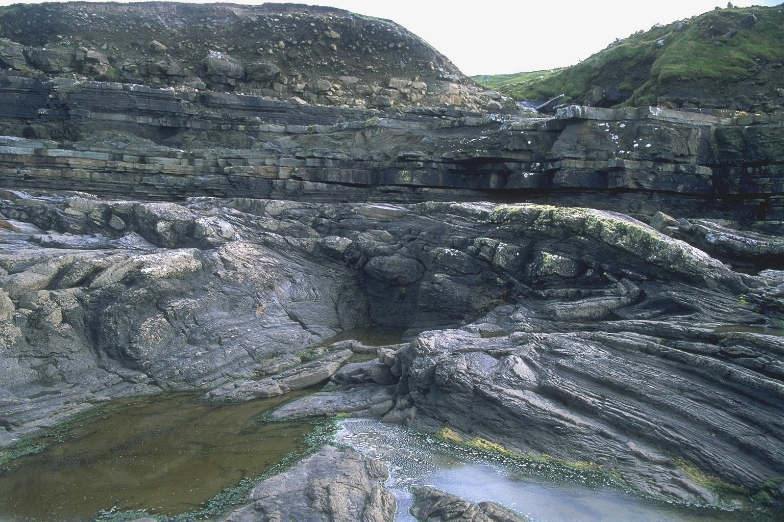 The Gull island Formation slope succession exposed at Fisherstreet, north County Clare. The folded sediments in the front are part of the Fisherstreet Slide, a major mass-transport complex and overlain by an undeformed package of sheet turbidites cap
