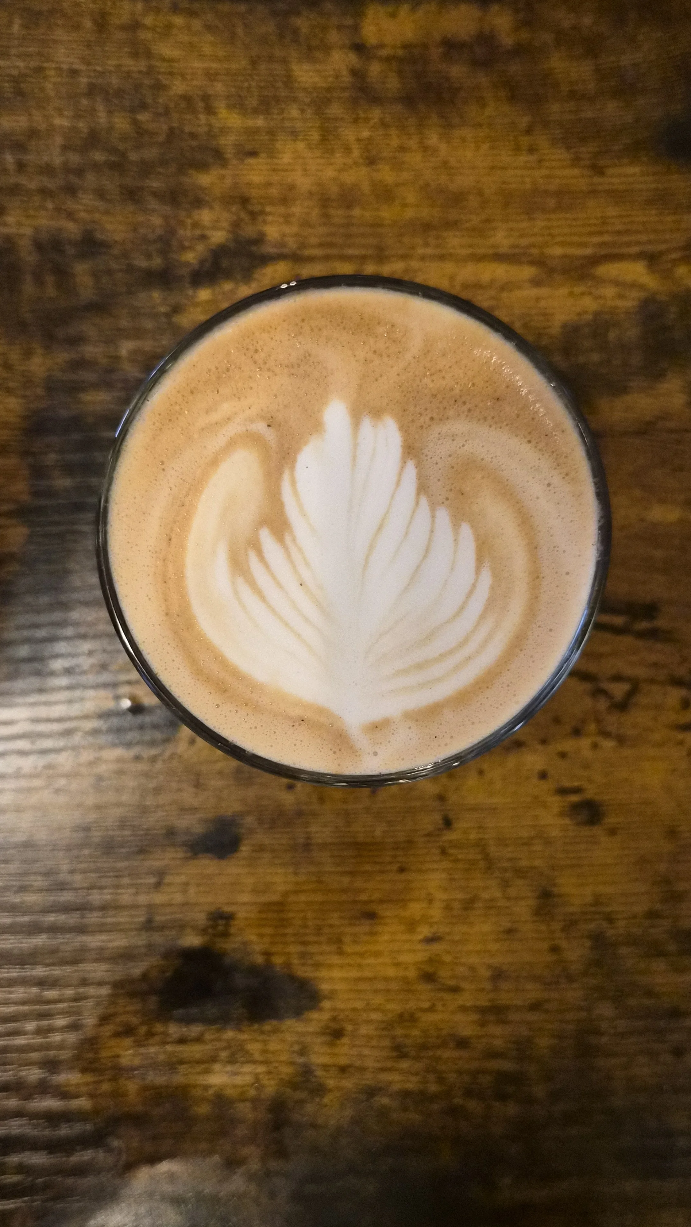 Latte with leaf latte art on wooden bench