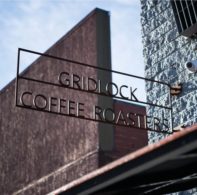 Metal sign reading 'Gridlock Coffee Roasters' hanging outside a building.