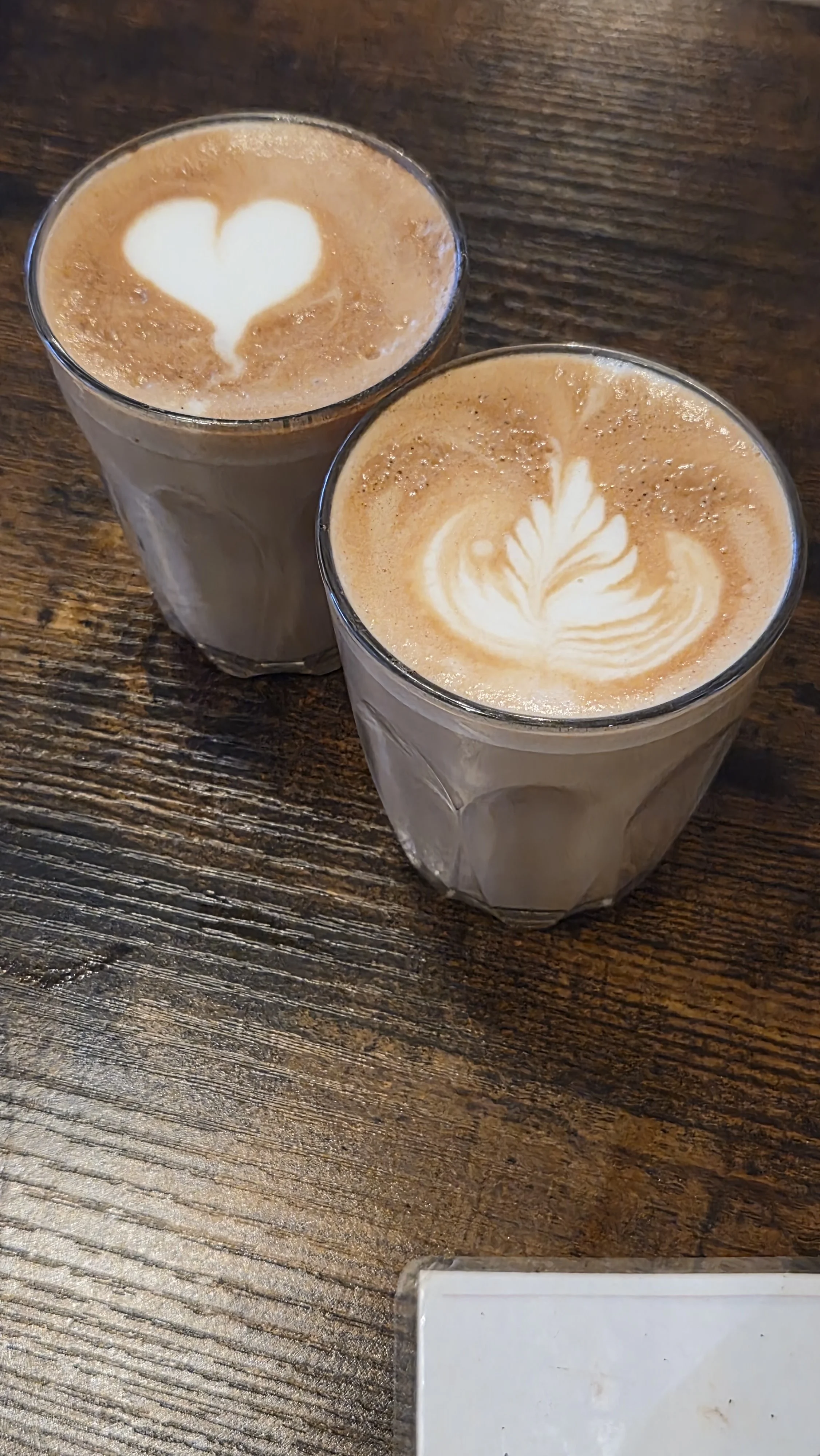 Lattes with latte art on wooden bench