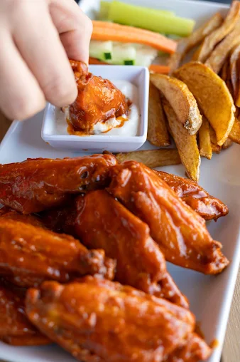Buffalo chicken wings with celery sticks, carrot sticks, and a side of ranch dipping sauce