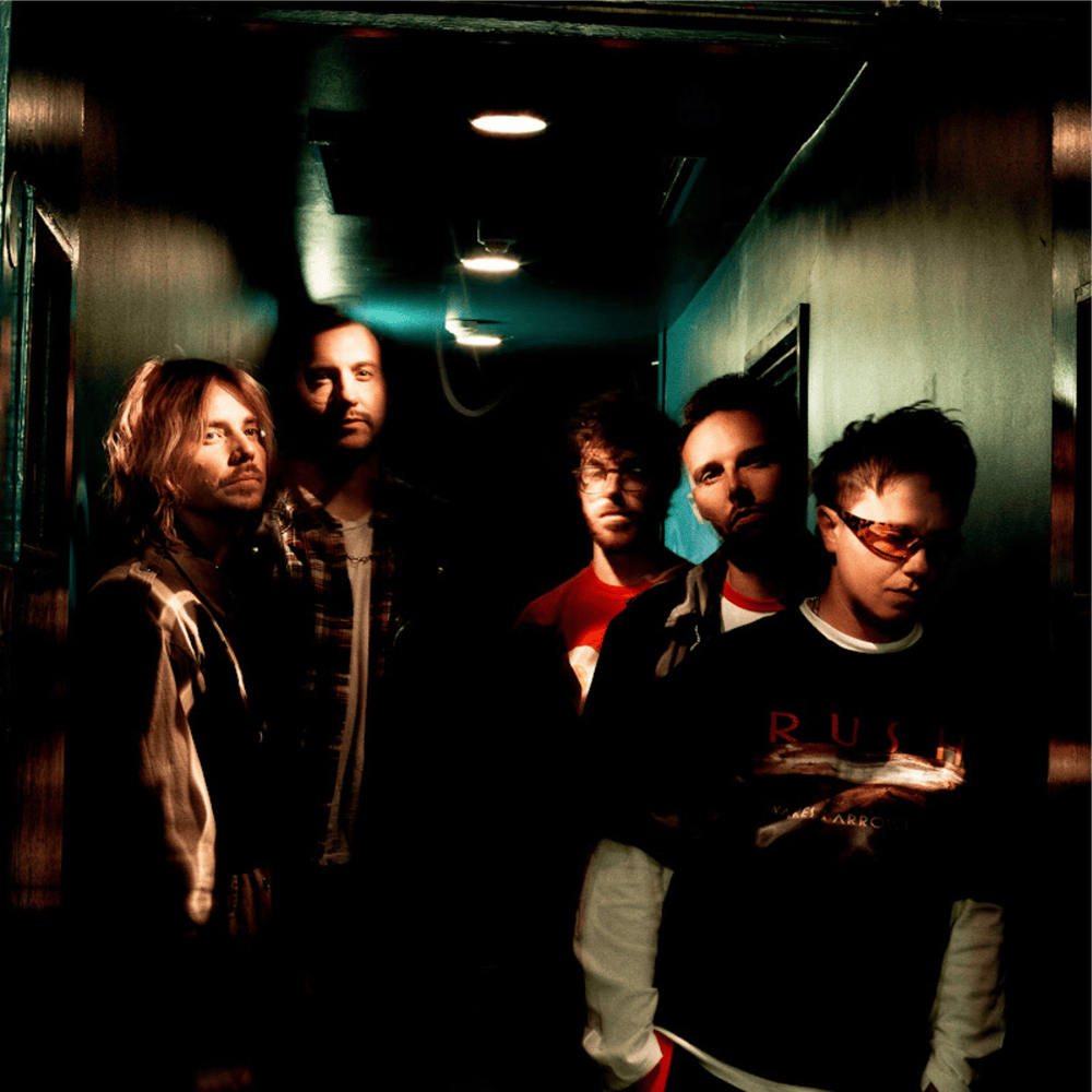 Five young men standing in a dark, narrow hallway with dim lighting.