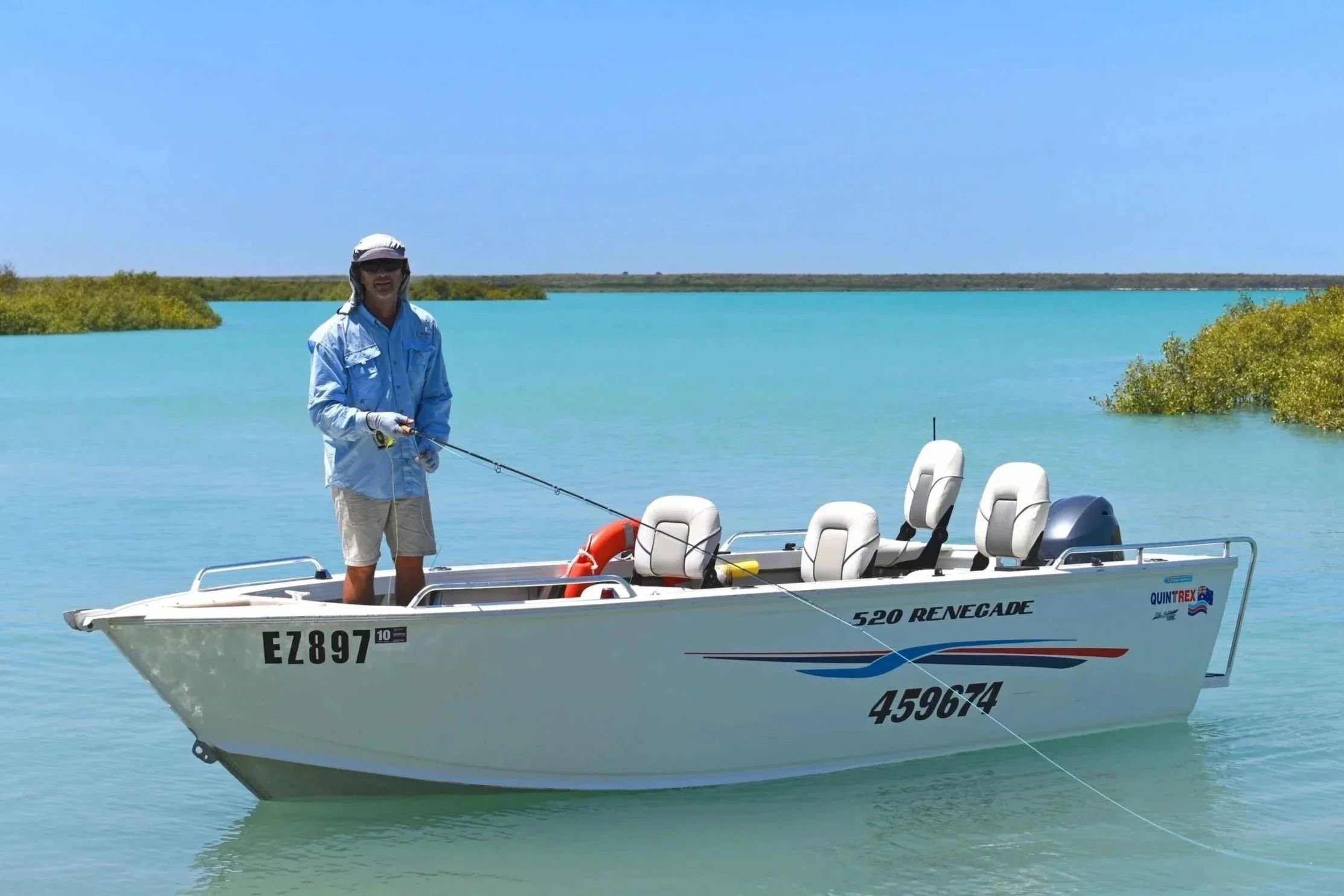 Landscape image of a white, 5.5 metre open boat in the waters of Broome's Bay. 4 passenger seats in the boat with the fisherman standing at the front while fly fishing.