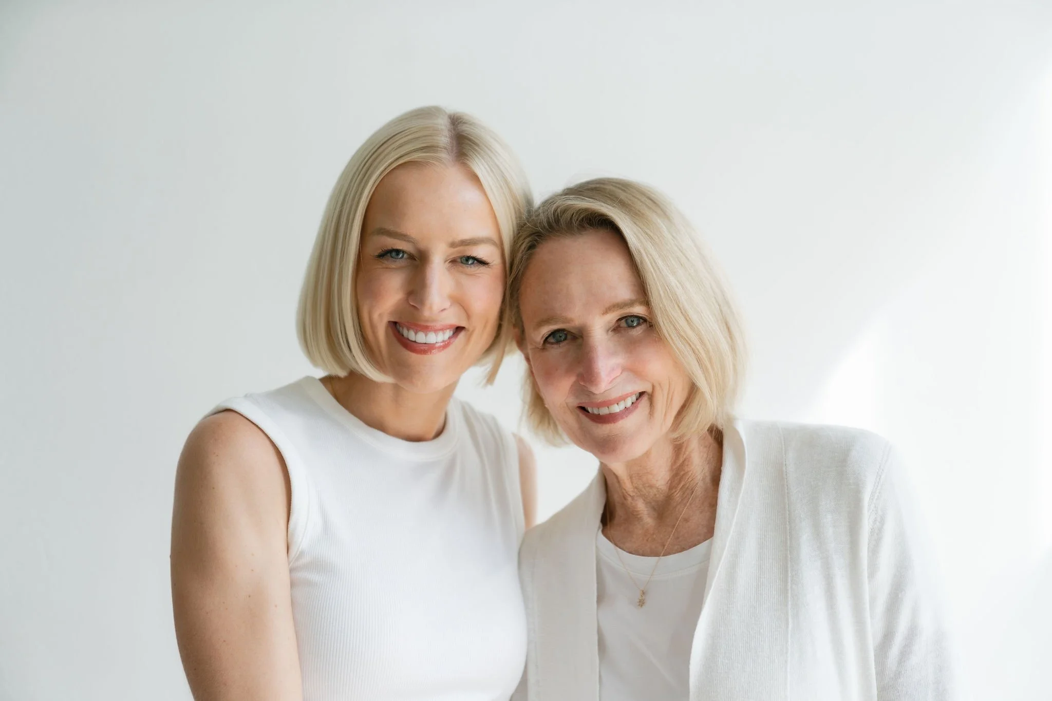 Two smiling women with blonde hair, wearing white tops are Sherry and Chelsea Ortega, a Bend Real Estate Agency.