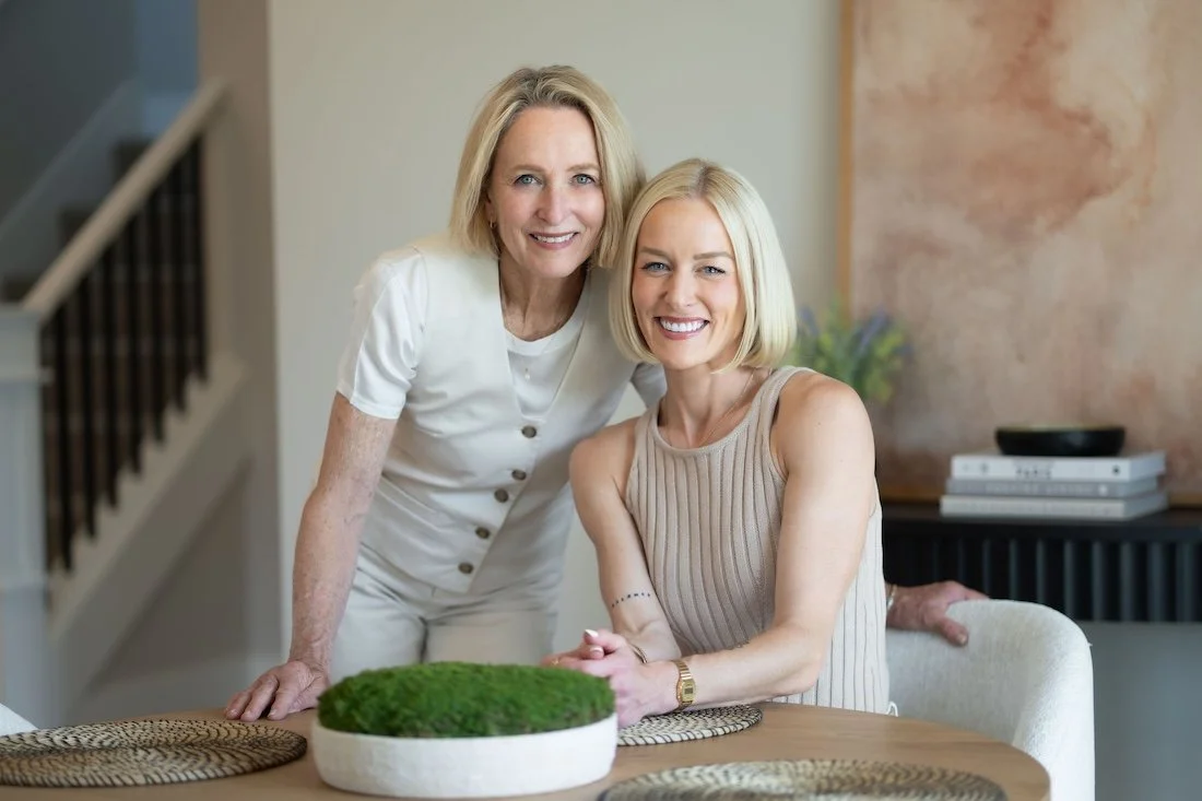 Two women, smiling in a home with a round table, green centerpiece, photographed in a  Northwest Crossing Bend Oregon Real Estate listing.