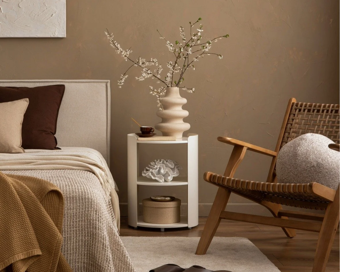 A harmonious colored bedroom with an armchair, night stand and artwork.