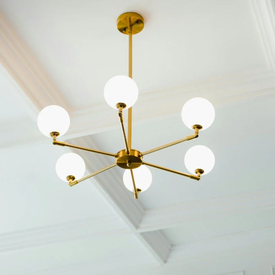 Modern brass chandelier with white globe lights for home listing in Bend Oregon Real Estate.