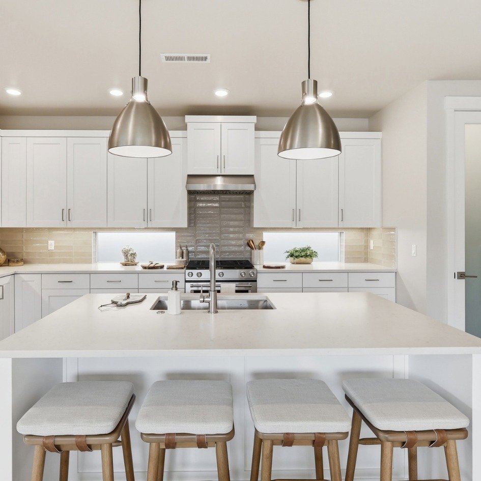 Modern kitchen with white cabinets, a large island with seating, stainless steel appliences for Bend Home for Sale listing.