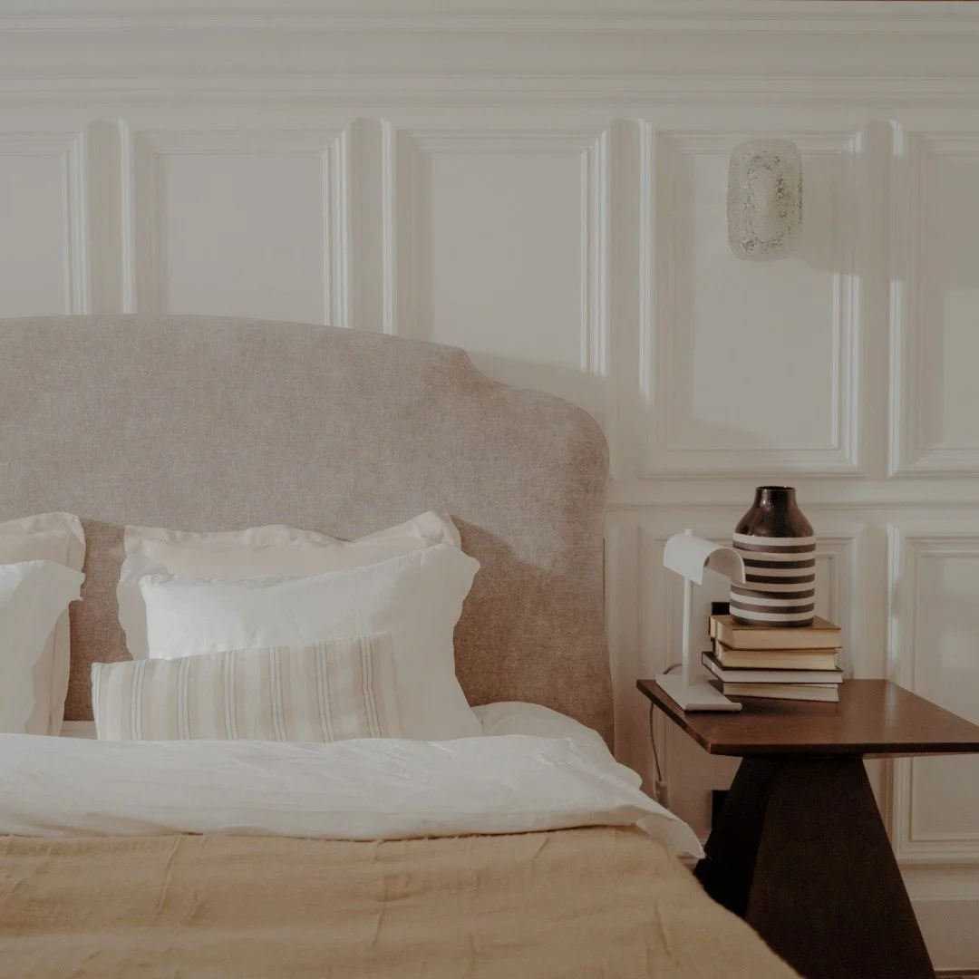 A bedroom with a beige upholstered headboard with bright bedding. A listing photo for Bend Real Estate market westside home.