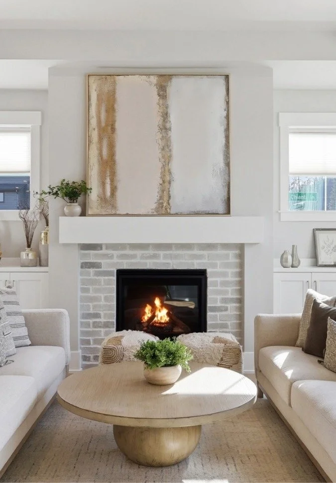 Living room, a fireplace, white sofas, a round wooden coffee table with a potted plant, and art for Bend Real Estate Agency photos.