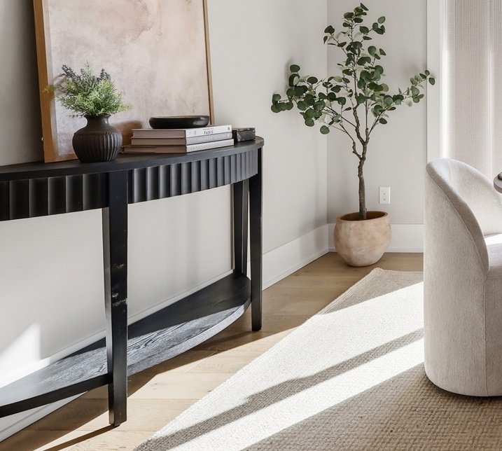 A black side console table, artwork, and decor with a potted plant for Bend Oregon Home for sale by The Ortega Collective.