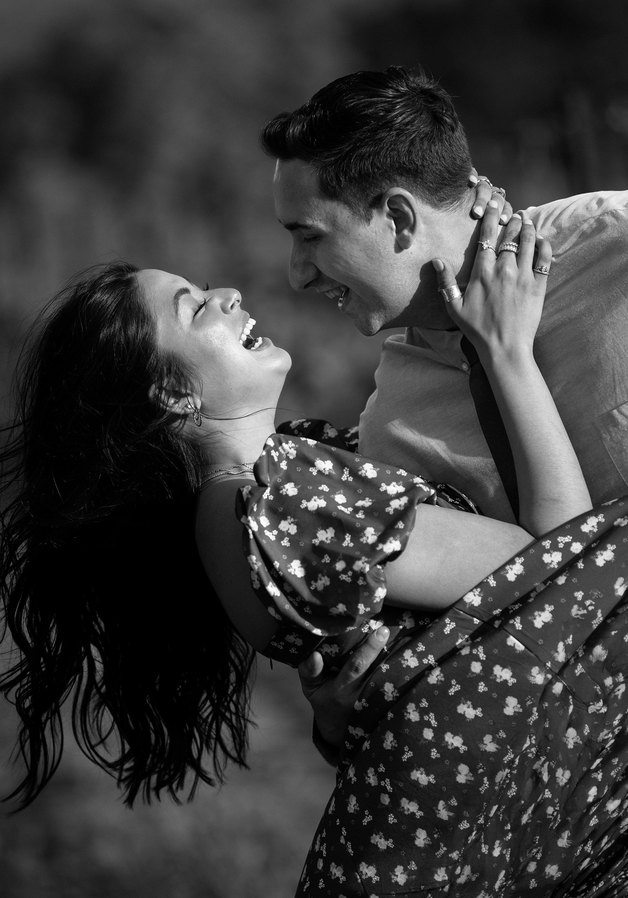 Black-and-white engagement portrait of a couple laughing and embracing during their Central Coast California engagement session.