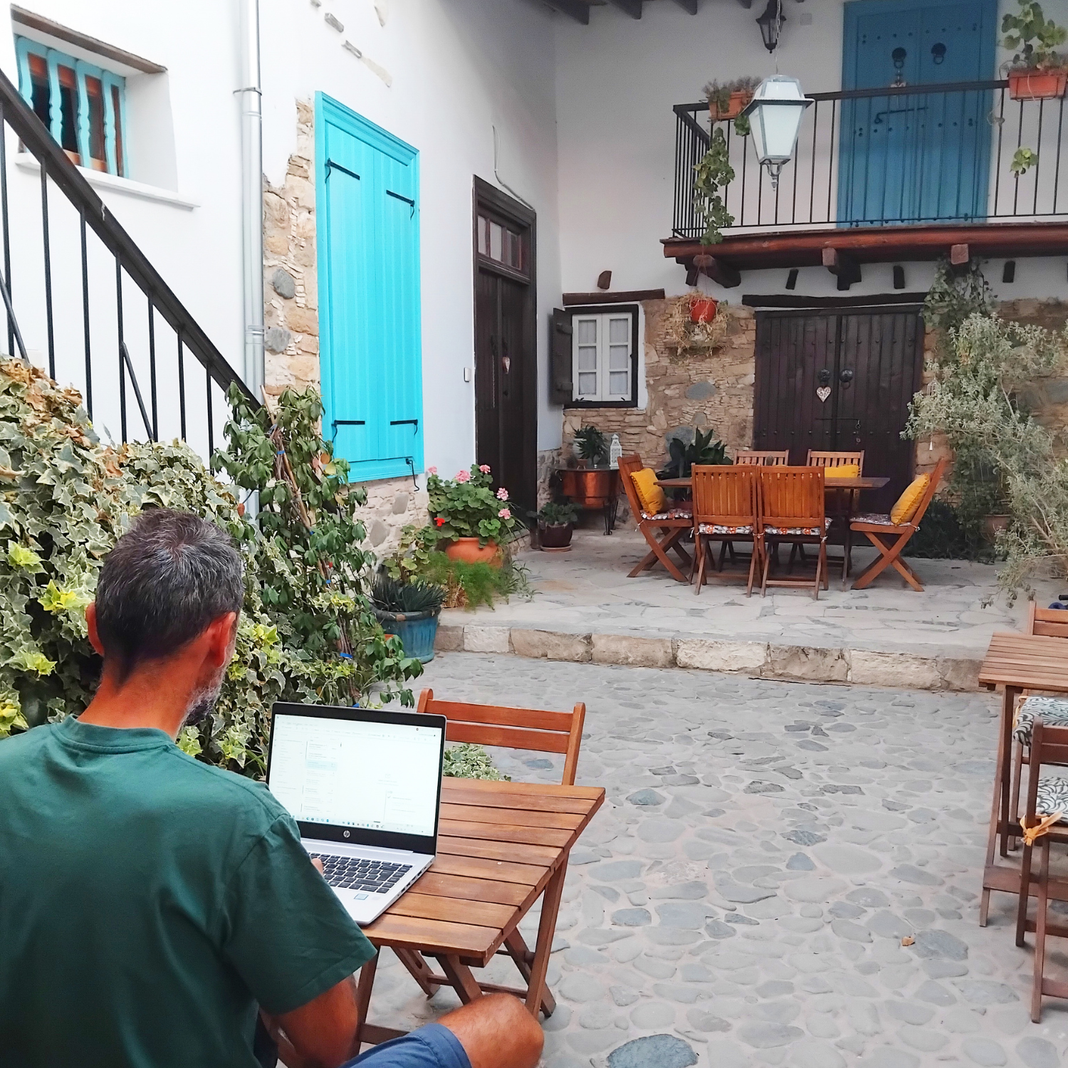 Tassos working on a laptop in Aperanti courtyard