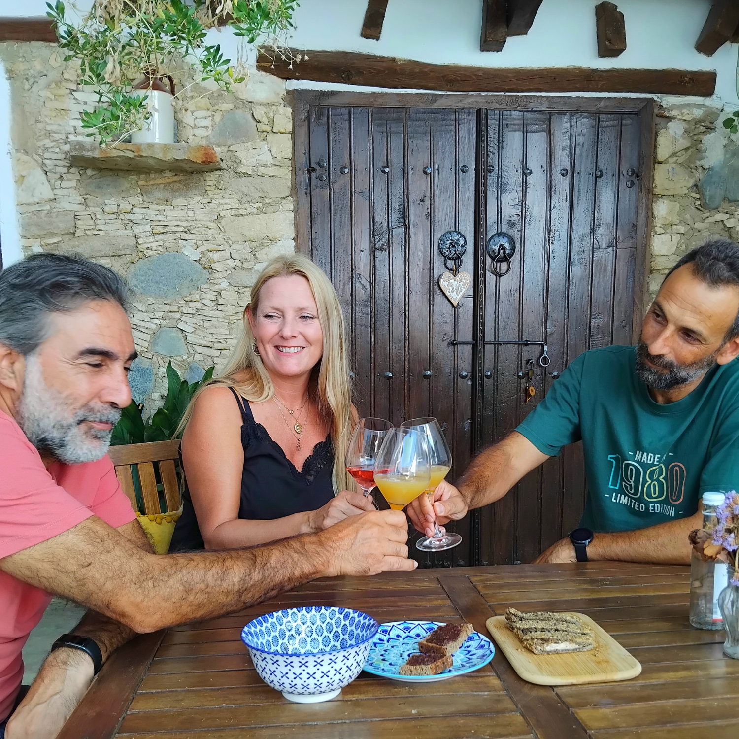 three people sitting on a table toasting with drinks