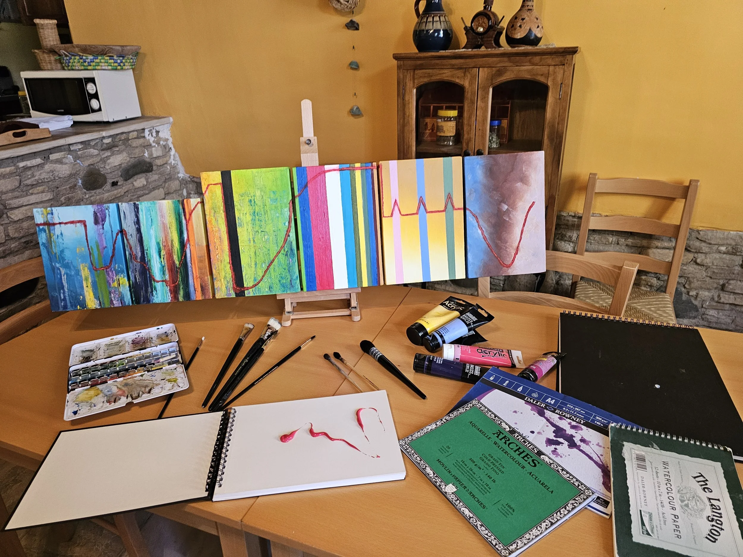 A table with colors and a painted canvas