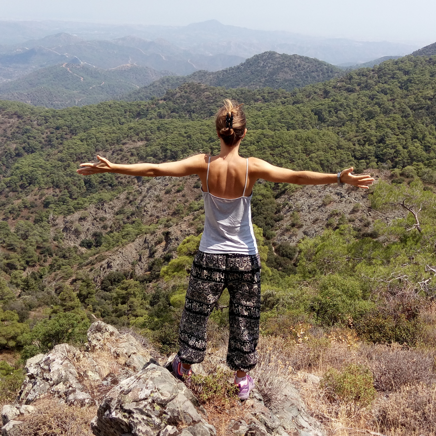 Woman standing on a stone looking at the mountains in the distance