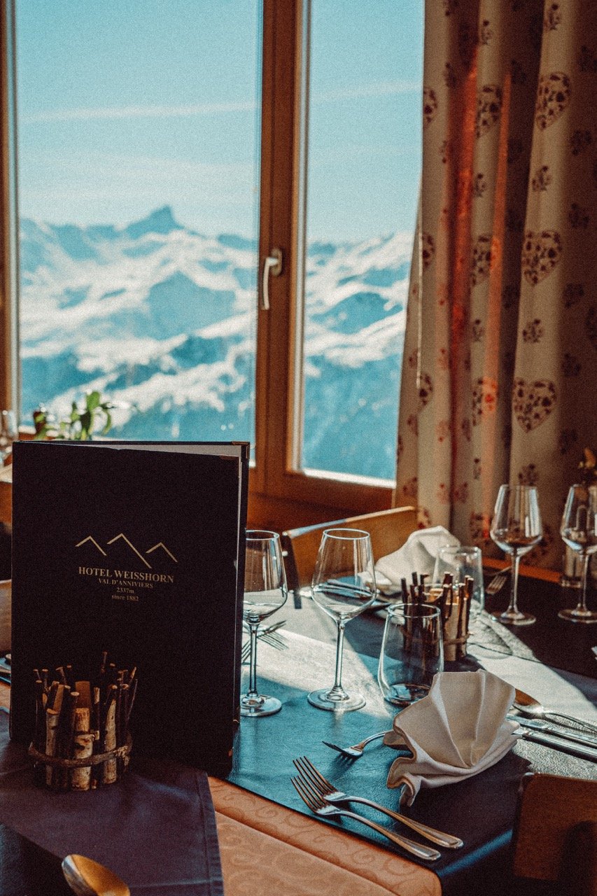 A fully dressed restaurant dining table with a view on snowy montains in the background