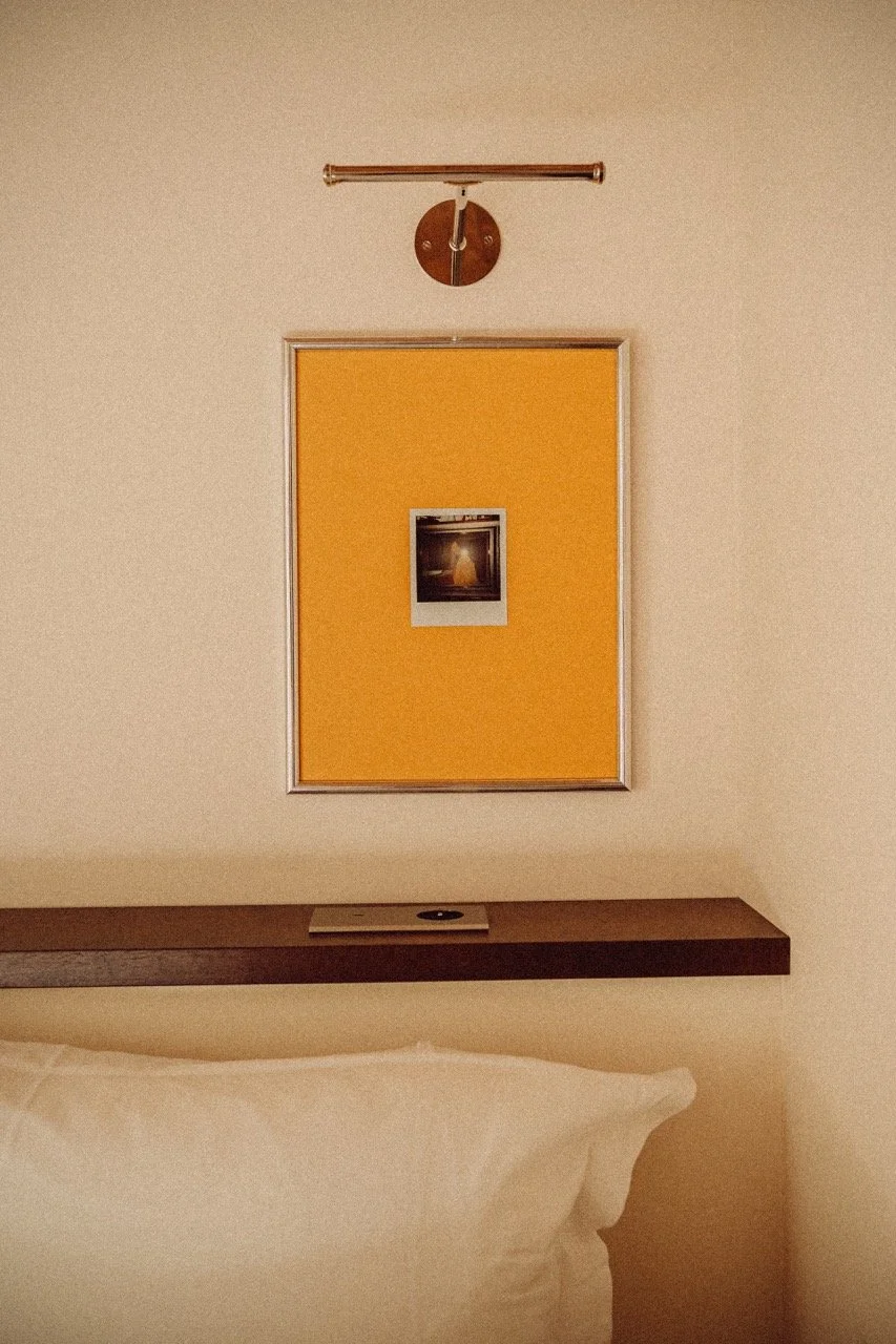 A close-up view of an art piece standing above a hotel bed and pillow