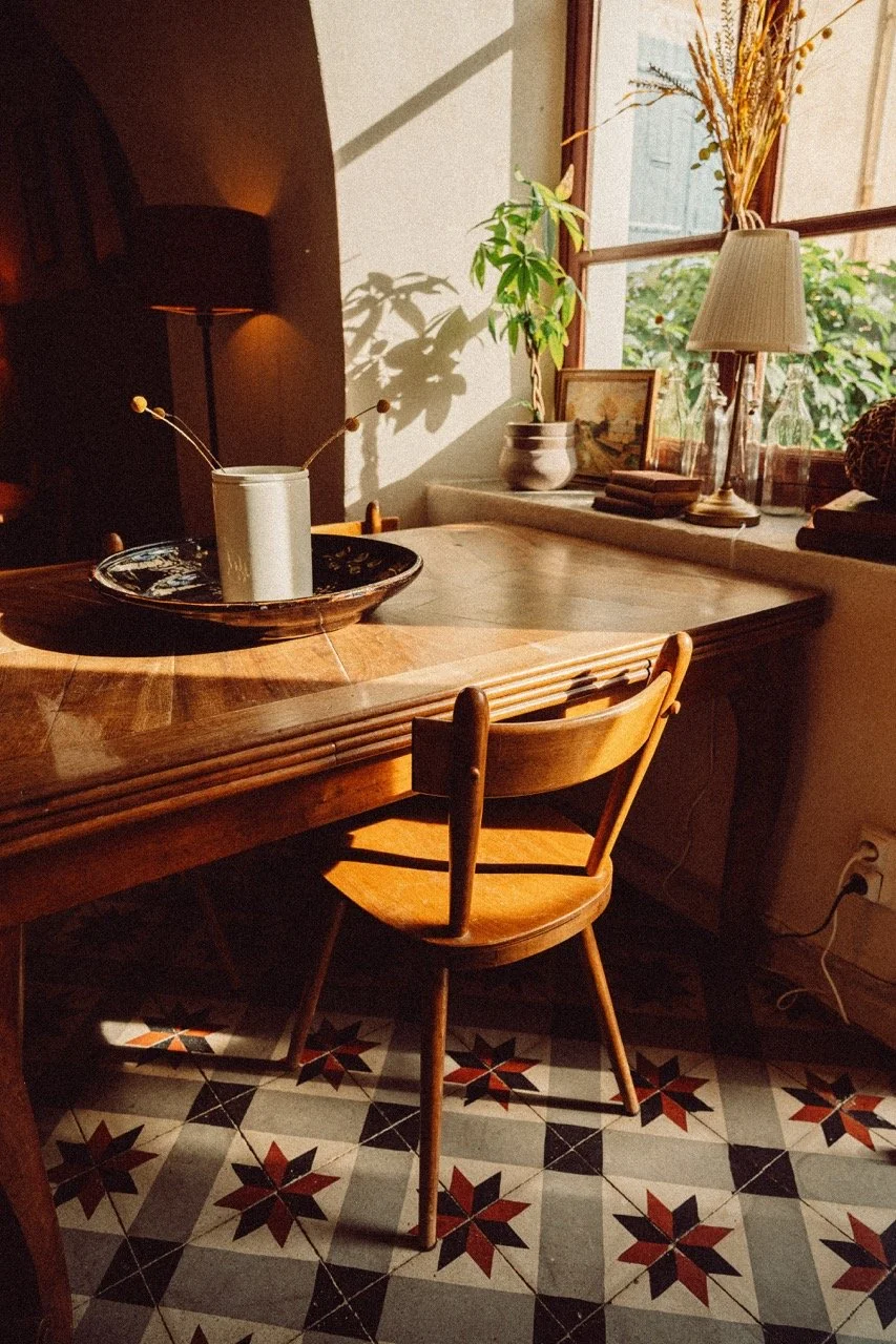 A sunny hotel dining room with a wooden chair and table on a provencal floor and plant by the window