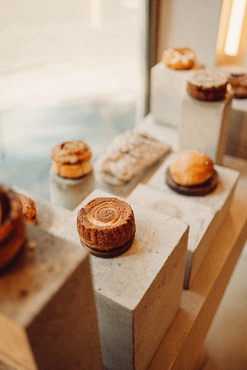 Assorted pastries displayed on white platforms in a bakery or cafe setting.