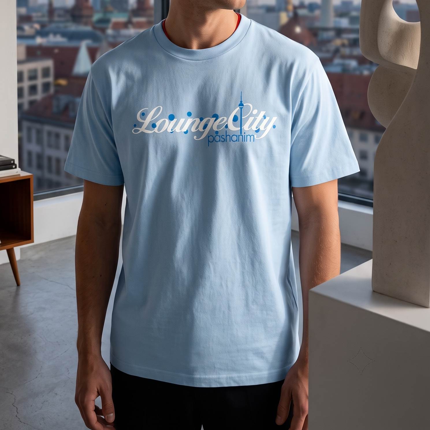 Person trägt ein hellblaues T-Shirt von Pashanim mit dem Logo "Lounge City pashanim" auf einem Stadtbild im Hintergrund.